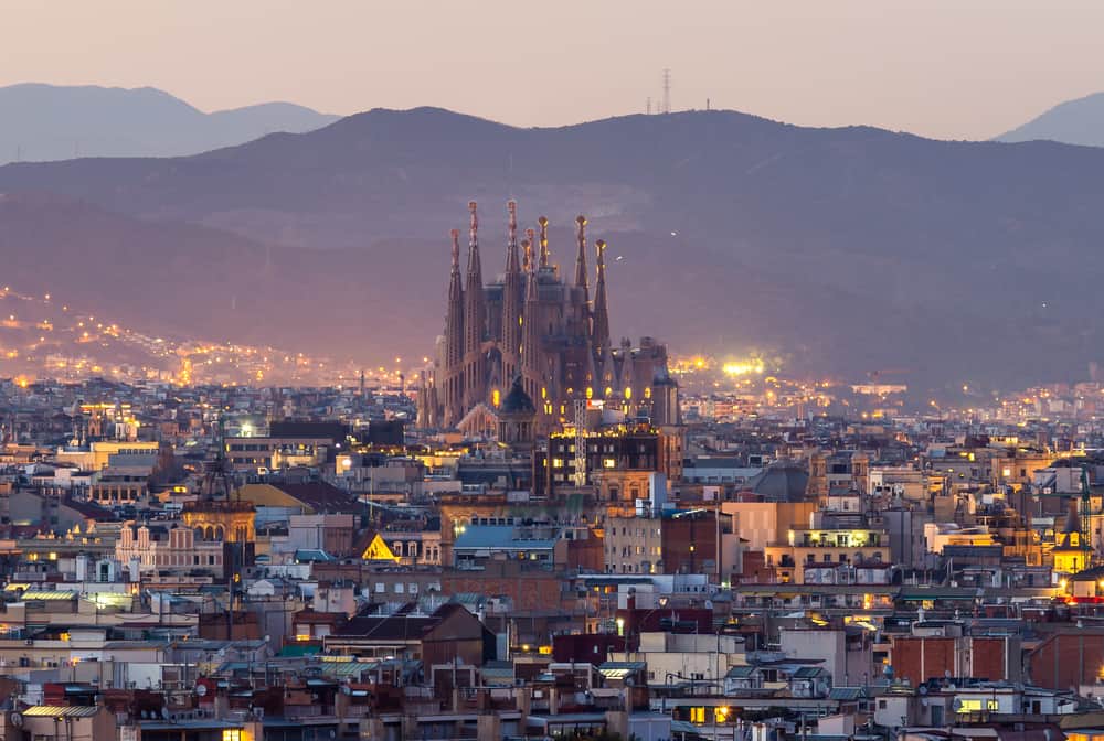 View over Barcelona-bydelen Eixample i skumringen med Sagrada Familia i baggrunden