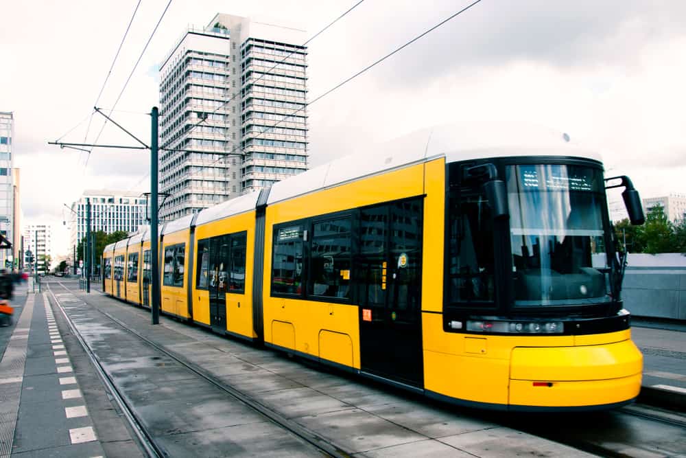 Gult U-Bahn tog ved Alexanderplatz i Berlin med højhus i baggrunden