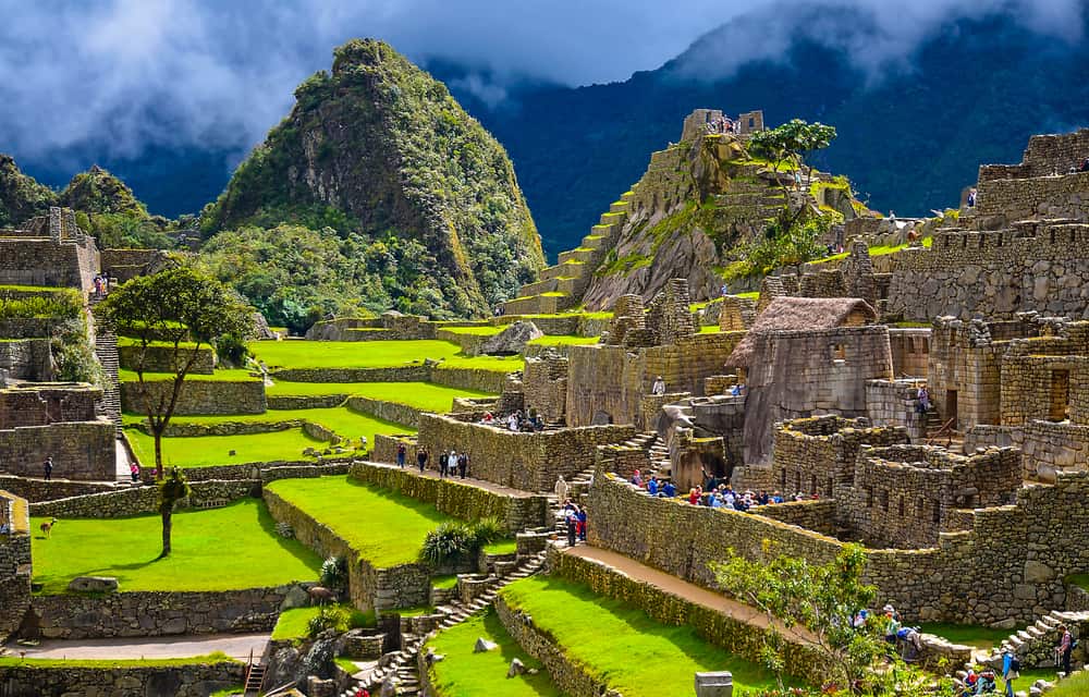 Turister der besøger inkabyen Machu Picchu i Peru