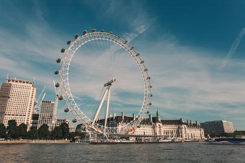 Fuld view af London Eye i England med floden Themsen i forgrunden.